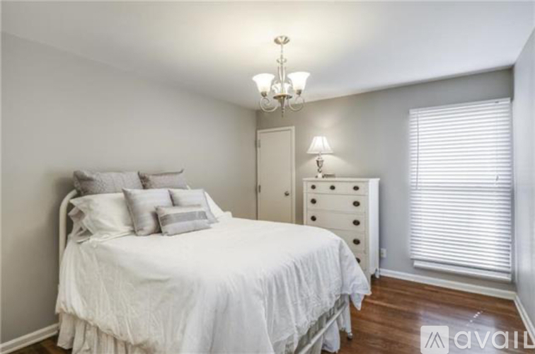 A bedroom with a white bed, a chandelier, and a white dresser.
