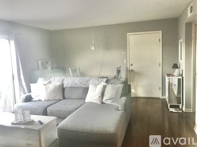 A bedroom with a grey couch and a white bedspread.