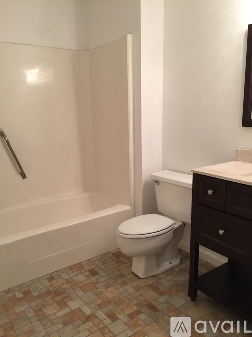A white toilet sits in a bathroom next to a white bathtub.