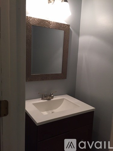 A bathroom sink with a brown framed mirror above it.