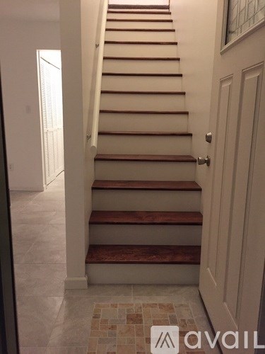 A staircase with a tiled floor and a white door.