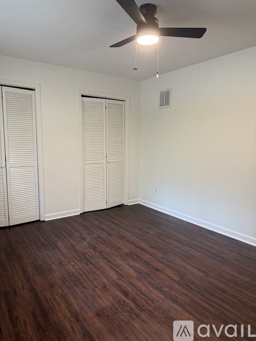 A room with a ceiling fan and wood flooring.