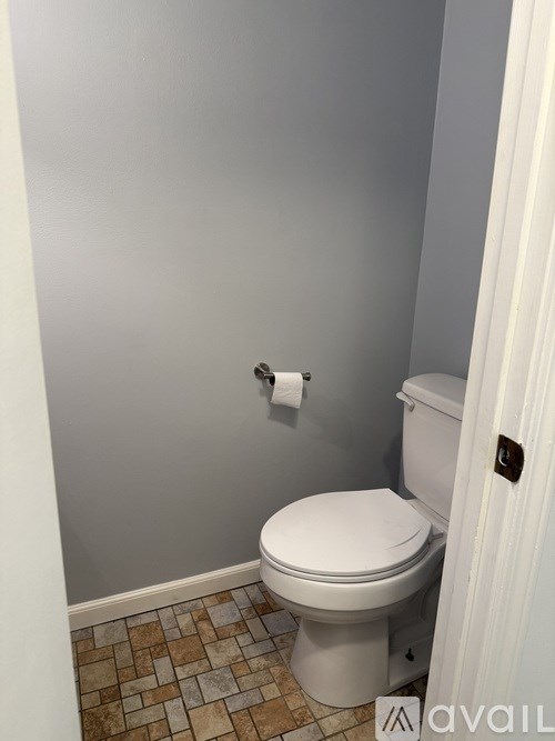 A white toilet in a bathroom with a tiled floor.