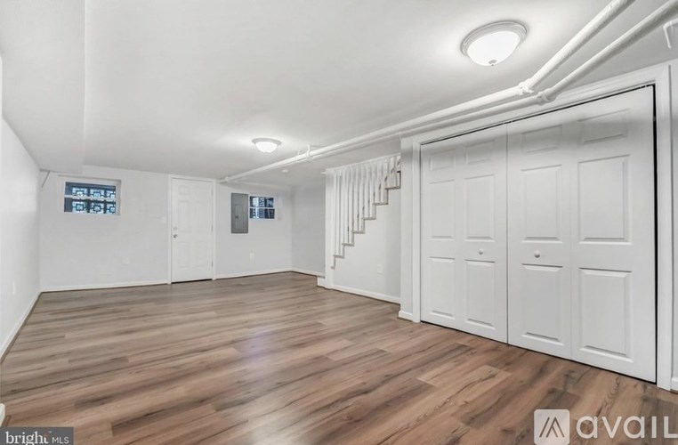 A room with white walls and wooden flooring, with a sign that reads "AVAILABLE".