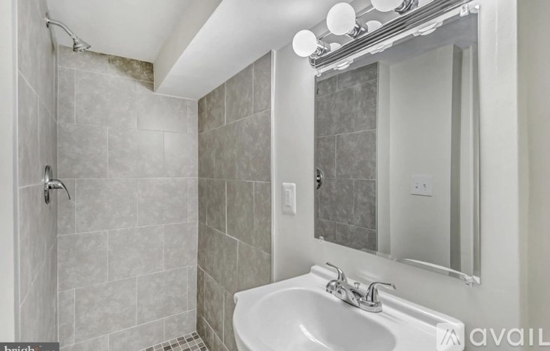 A bathroom with a white sink and a shower with a glass door.