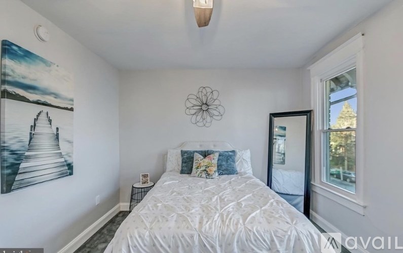 A bedroom with a large bed and a painting on the wall.