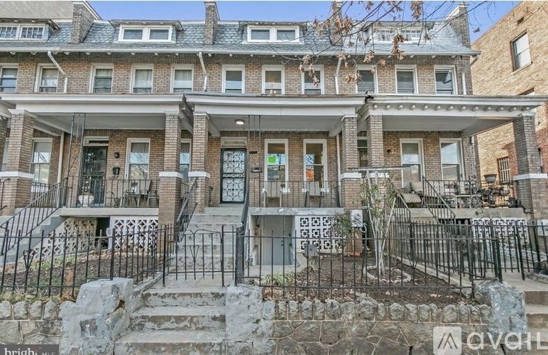 A row of brown brick townhouses with green shutters.