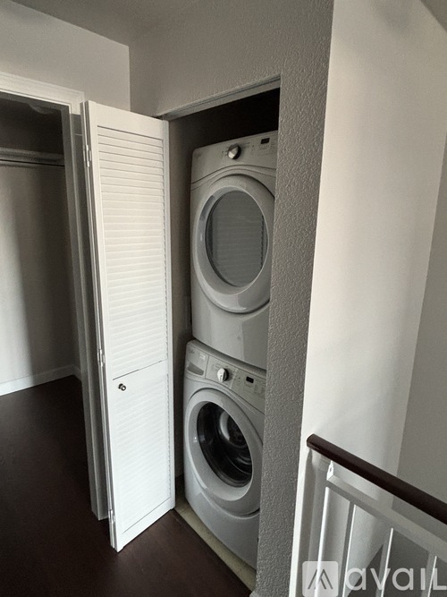 A white washing machine is in a small space between a wall and a door.
