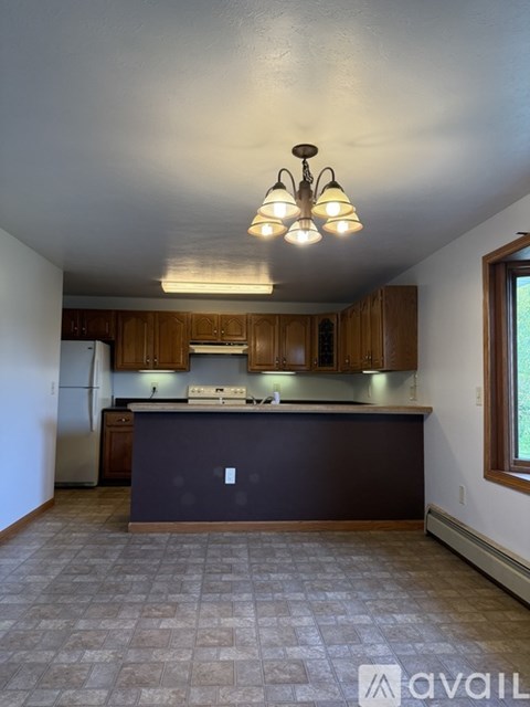 A kitchen with brown cabinets and a dark island.