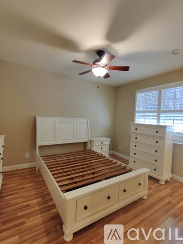 A bedroom with a bed, dresser and window.
