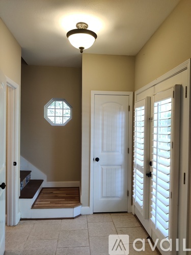 A hallway with a white door and a window with a wooden frame.