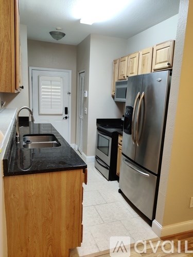 A kitchen with wooden cabinets and a stainless steel refrigerator.