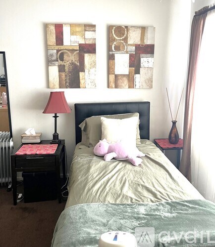 A bedroom with a bed, a nightstand with a lamp, and a painting on the wall.