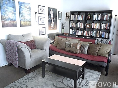 A living room with a couch, chair, and bookshelf.
