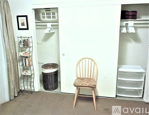 A chair sits in front of a white closet with shelves and a laundry basket.
