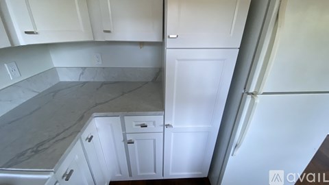A kitchen with white cabinets and a marble countertop.