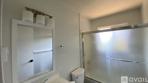 A bathroom with a toilet, sink, and mirror.