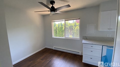 A room with a ceiling fan and a window overlooking trees.
