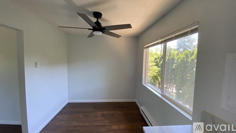 A room with a ceiling fan and a window overlooking trees.