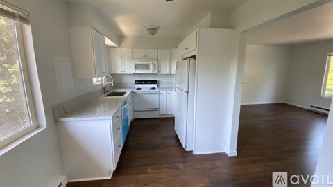 A kitchen with white cabinets and a wooden floor.