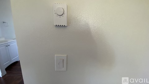 A wall-mounted thermostat is installed on a wall next to a light switch.