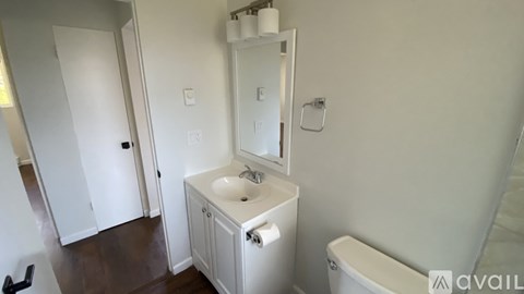 A white bathroom with a sink, mirror, and toilet.