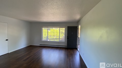 A room with a window and wooden floors is available for rent.