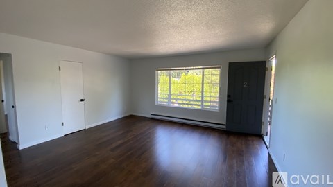 A room with wooden floors and a window showing greenery outside.