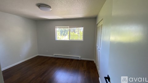 A room with wooden floors and a window with blinds.