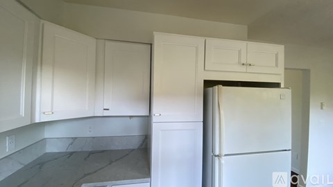 A kitchen with white cabinets and a white refrigerator.