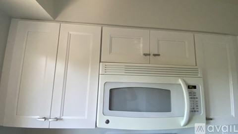 A white microwave oven is built into a white cabinet.