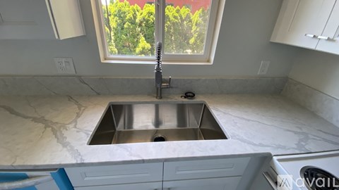 A kitchen with a marble countertop and a window above the sink.