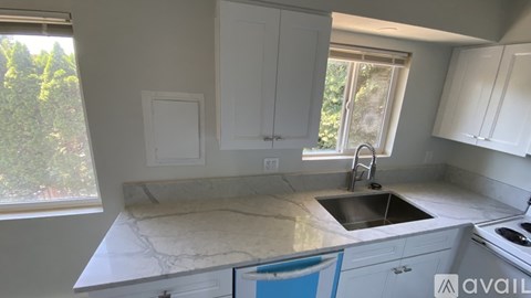 A kitchen with white cabinets and a marble countertop.