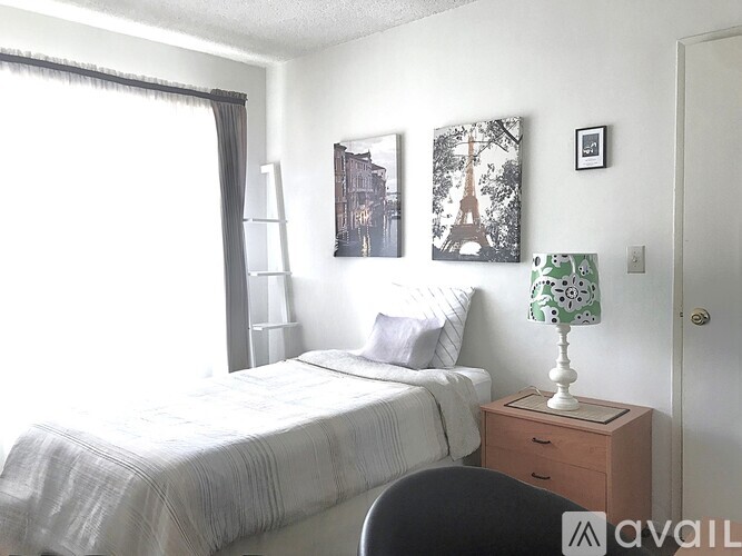 A bedroom with a bed, nightstand, chair, and pictures on the wall.