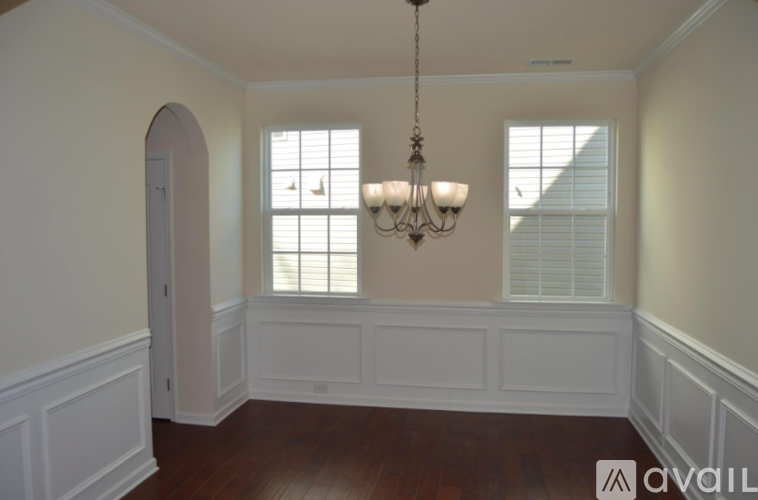 A room with a chandelier and a window with blinds.