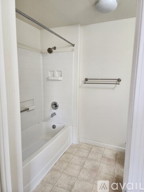 A white bathroom with a tub and a towel bar.