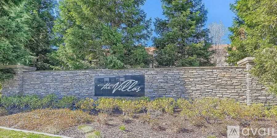 A sign that says "The Village" is mounted on a stone wall.