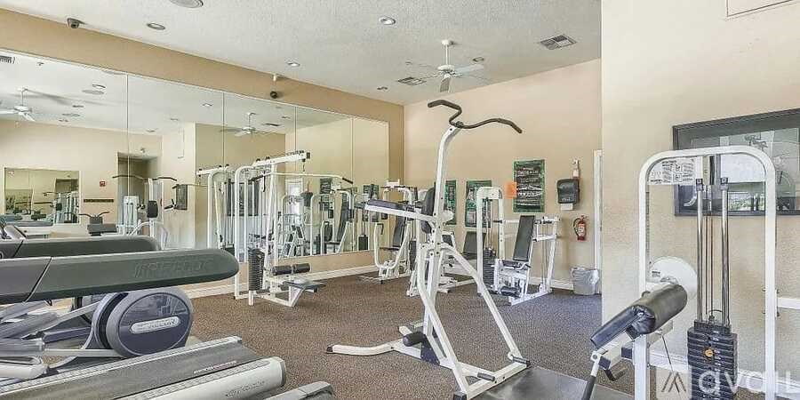 A gym with a variety of equipment including treadmills, weights, and exercise machines.