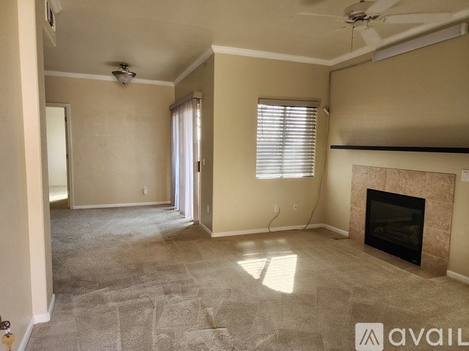 A living room with a fireplace and a fan on the ceiling.