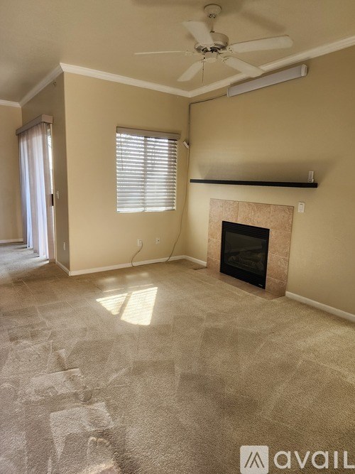 A living room with a fireplace and a fan on the ceiling.