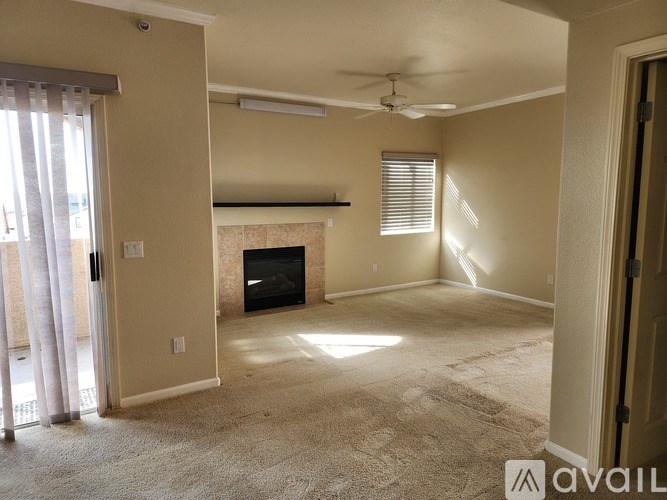 A living room with a fireplace and a ceiling fan.
