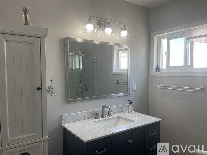 A bathroom with a sink, mirror, and lighting fixture.
