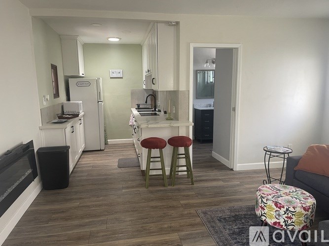 A kitchen with a refrigerator, stove, and bar stools.