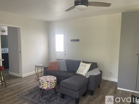 A living room with a grey couch and a floral ottoman.