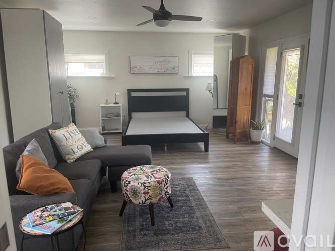 A bedroom with a bed, a couch, and a ceiling fan.