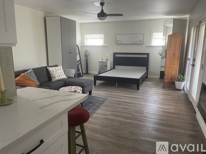 A bedroom with a bed, couch, and a fan.