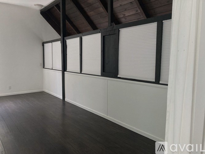 A room with a wooden ceiling and dark wood flooring.