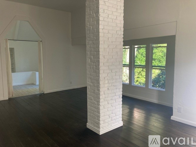 A white interior with a brick pillar and wooden floors.