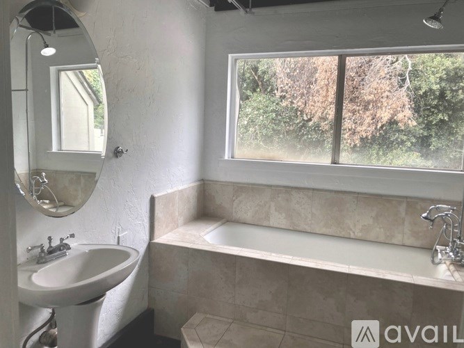 A bathroom with a tub, sink, and mirror.