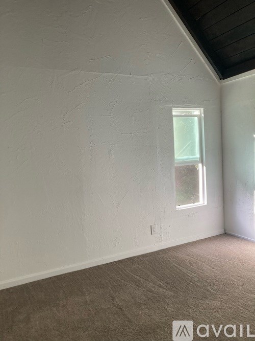 A room with a window and a wall with a rough texture.